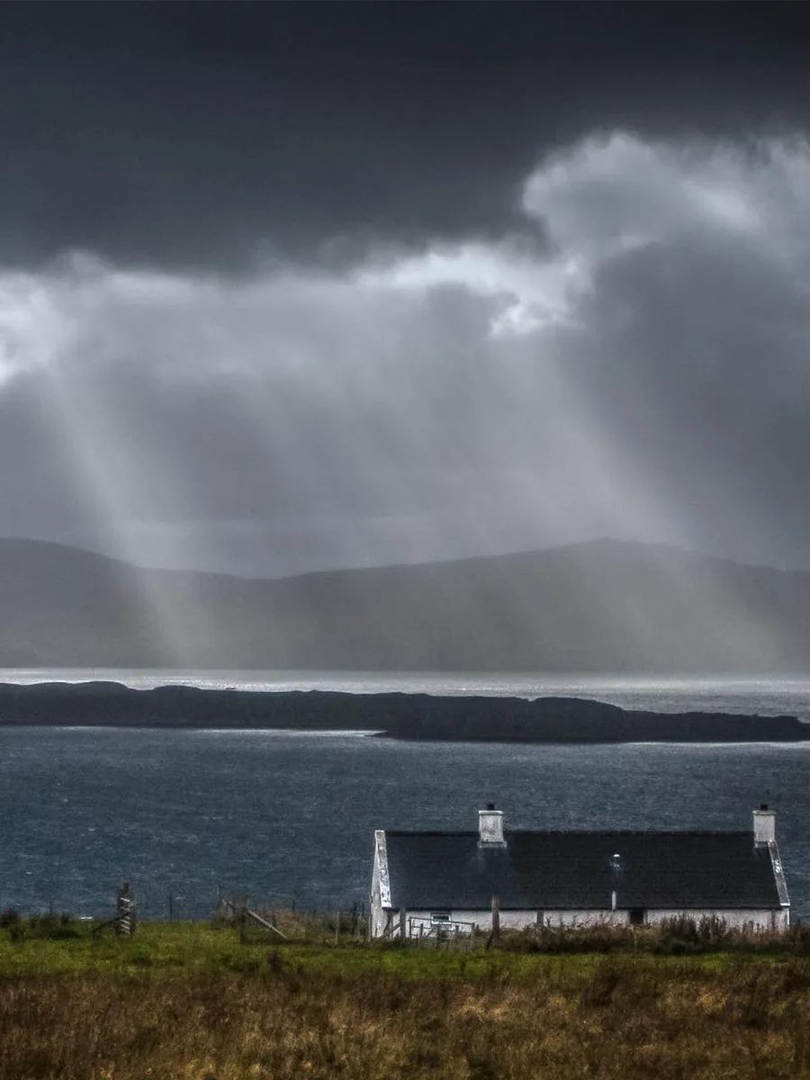 Shafts of light breaking through storm cloud over Loch Bay